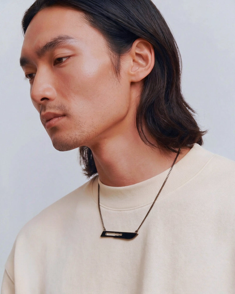The Kiran scalpel necklace in 18K gold with black rhodium finish by House of Rednam
